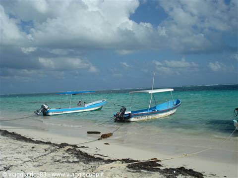 Blue fishing boats moored on the white shore under clouds
