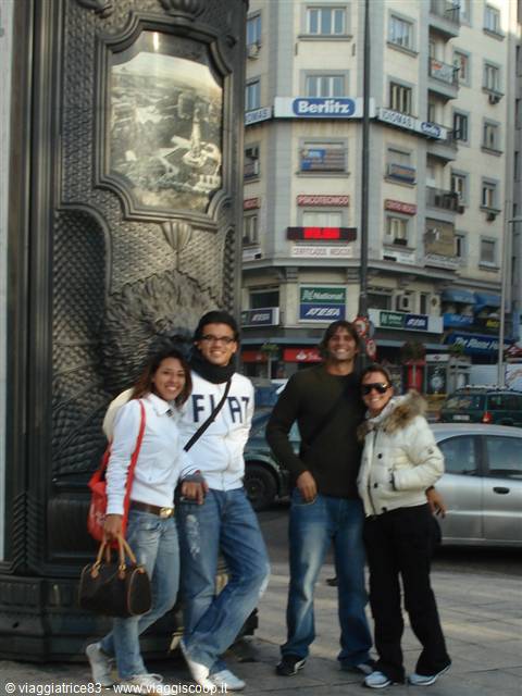 Four friends posing beside an ornate iron column in Belgrade
