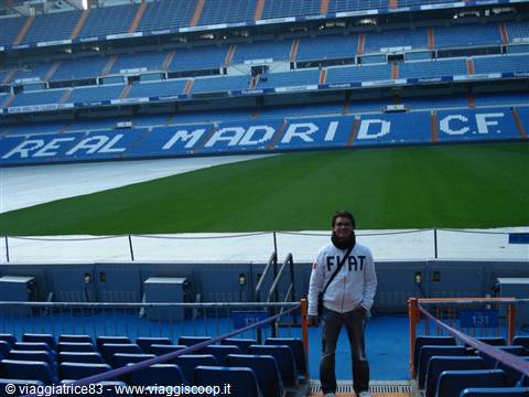 Tourist in the stands at Santiago Bernabéu stadium, blue seats and Real Madrid pitch