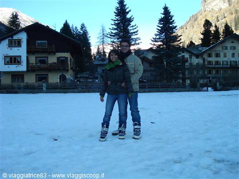 Couple in snow boots on snowy field among chalets and fir trees