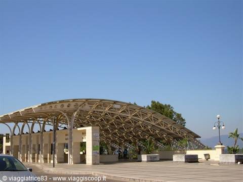 White travertine vaulted pavilion on a paved square under blue sky