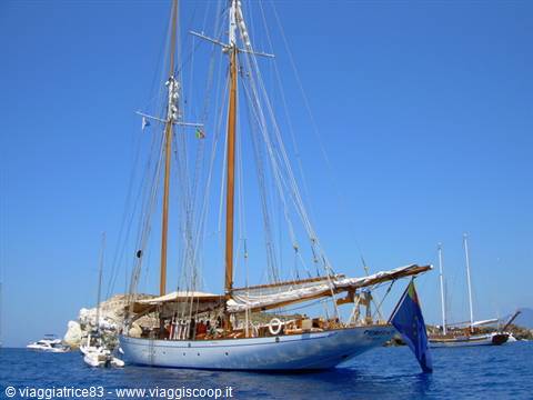 White wooden schooner anchored in a bay, tall masts, clear blue sky