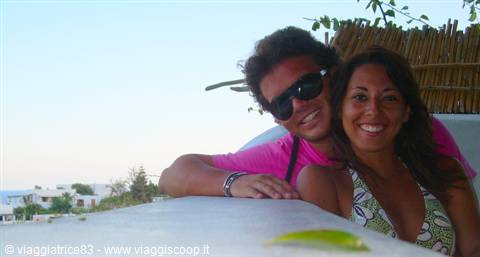 Smiling couple leaning on a white wall behind a woven cane screen
