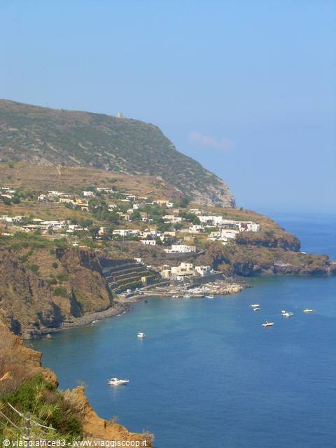 Boats anchored off a village of white houses on volcanic slopes