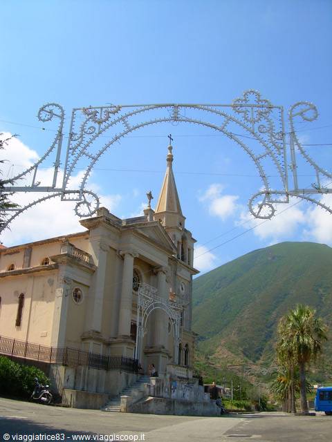 Church with bell tower and wrought-iron light arches, green mountains behind