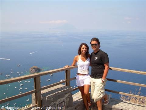 smiling couple beside a wooden railing above the sea in Capri