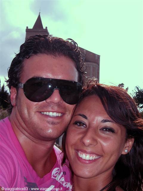 Smiling couple taking a selfie in front of Erice cathedral bell tower