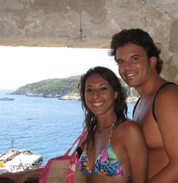 Smiling couple in swimwear under stone terrace above the blue sea