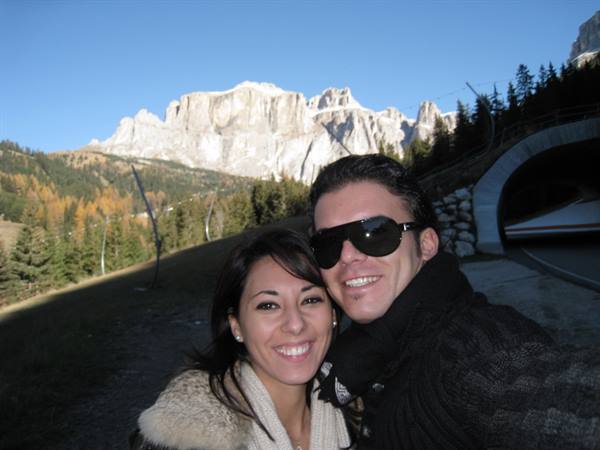 Smiling couple in front of Dolomite peaks and tunnel at Passo Gardena