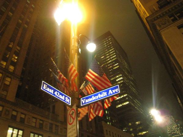 East 42nd St and Vanderbilt Ave signs with American flags, New York at night