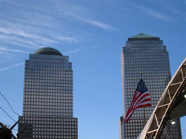 American flag waving in front of the glass towers of World Financial Center