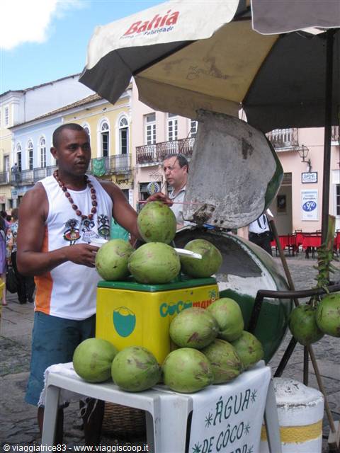Vendor opening green coconuts at a street stall under a Bahia umbrella