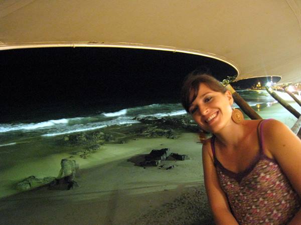 Smiling woman under a nighttime canopy by the beach waves