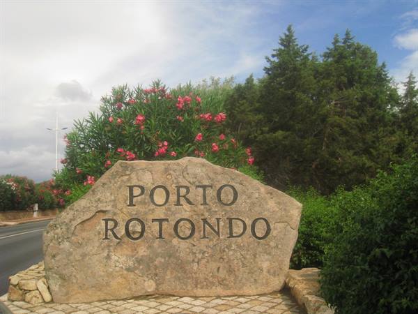 Stone boulder engraved Porto Rotondo among pink oleanders and pine trees