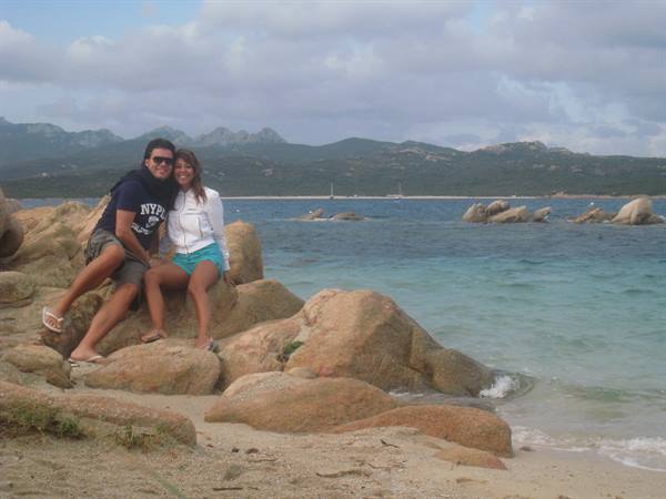 Couple sitting on granite rocks beside the turquoise sea in Costa Smeralda