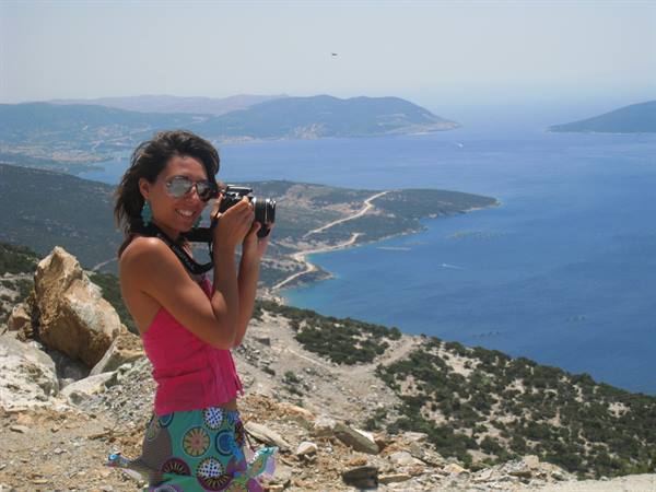 Woman with camera on rocky trail above the blue sea