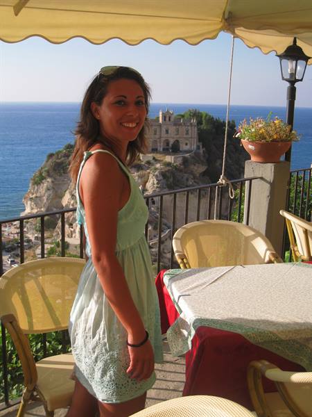 Smiling girl on a Tropea terrace, Santa Maria dell'Isola church behind her