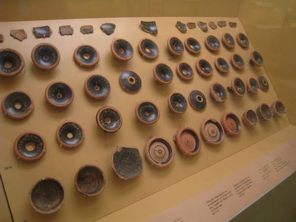 Museum display case with ancient ceramic cups and plates arranged in rows