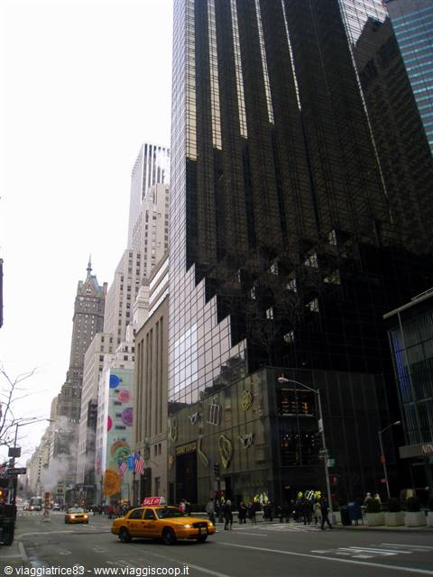 Yellow taxi passing Trump Tower's dark bronze glass on Fifth Avenue