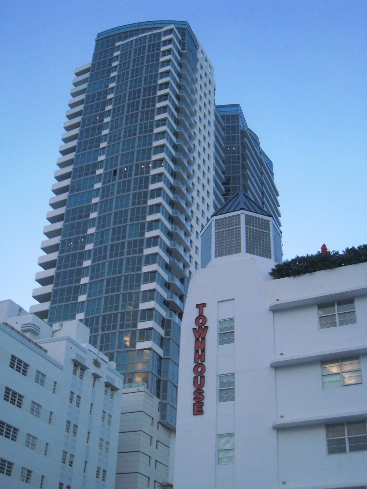 Glass skyscraper above white buildings with red Townhouse sign