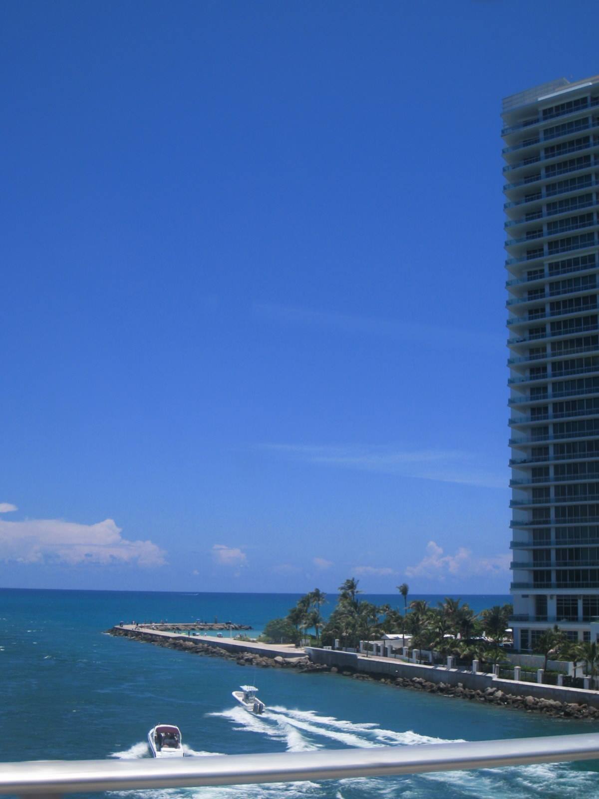 Speedboats racing along the coast past a Miami beach tower
