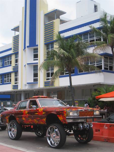 Lifted car with chrome rims in front of blue art deco building, Ocean Drive