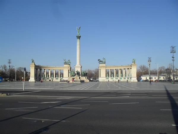 Heroes' Square in Budapest: stone millennium column between two neoclassical colonnades, blue sky