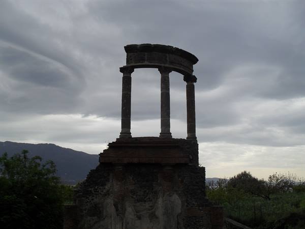 Pompeii: circular monument of Scaurus, stone columns beneath cloudy sky