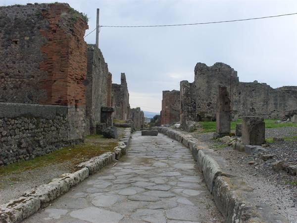 Stone-paved street between ancient ruined walls in Pompeii