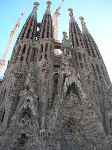 Sculpted façade of the Sagrada Família in Barcelona, stone spires against cranes