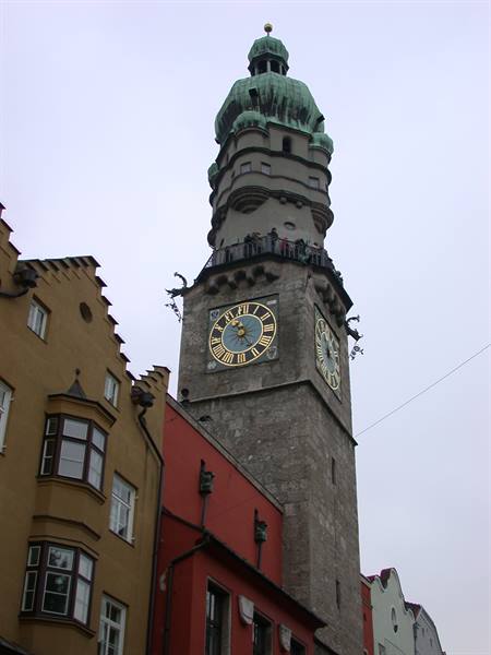 Clock tower with golden dial and tourists on the balcony, Innsbruck