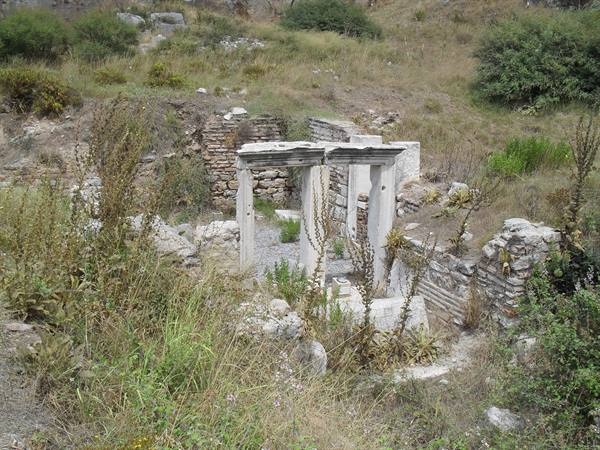 Marble ruins among dry grass and bushes, remains of columns and ancient walls