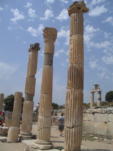 Tourists walk among carved marble Corinthian columns at ancient Ephesus