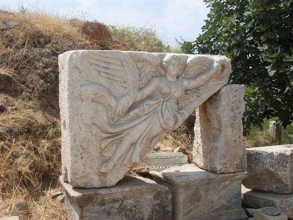 Marble relief of winged Nike goddess among ruins, Ephesus