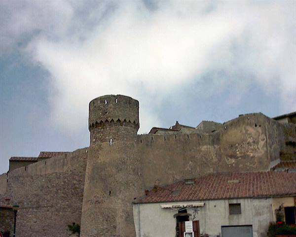 Round stone tower and medieval castle walls above terracotta-roofed houses