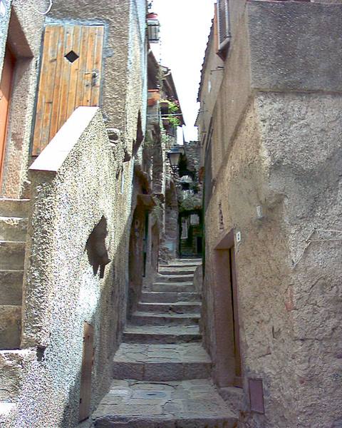 narrow stone alley with steps between old houses, wooden door and sunlight