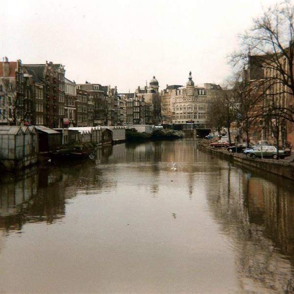 Amsterdam canal with merchant houses, houseboats and parked cars, grey winter light