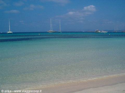 Sailboats anchored offshore, clear turquoise water and sandy beach