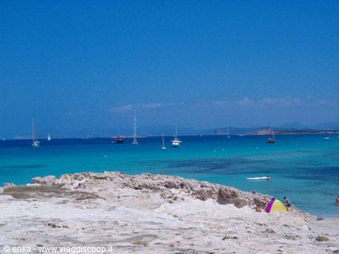 Sailboats anchored in turquoise water by white sandy shore
