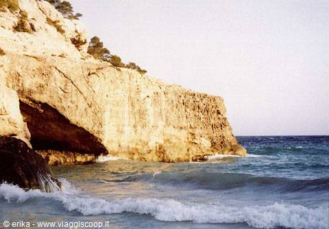 Foamy waves against the limestone cliff and cave on the coast