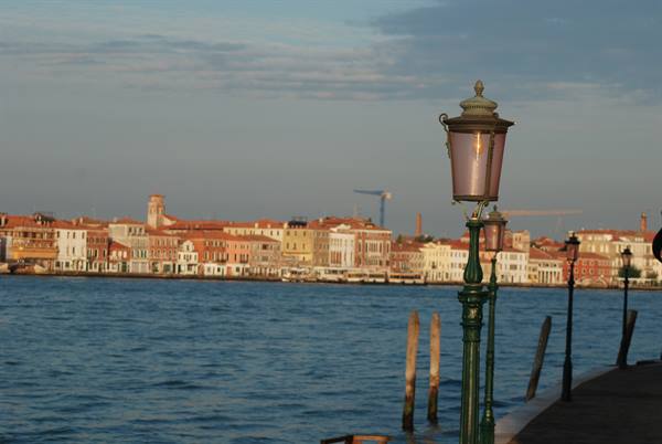Green lamppost on the waterfront facing the lagoon and Venice facades