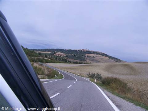 Winding asphalt road through plowed hills seen from a car window, Tuscany