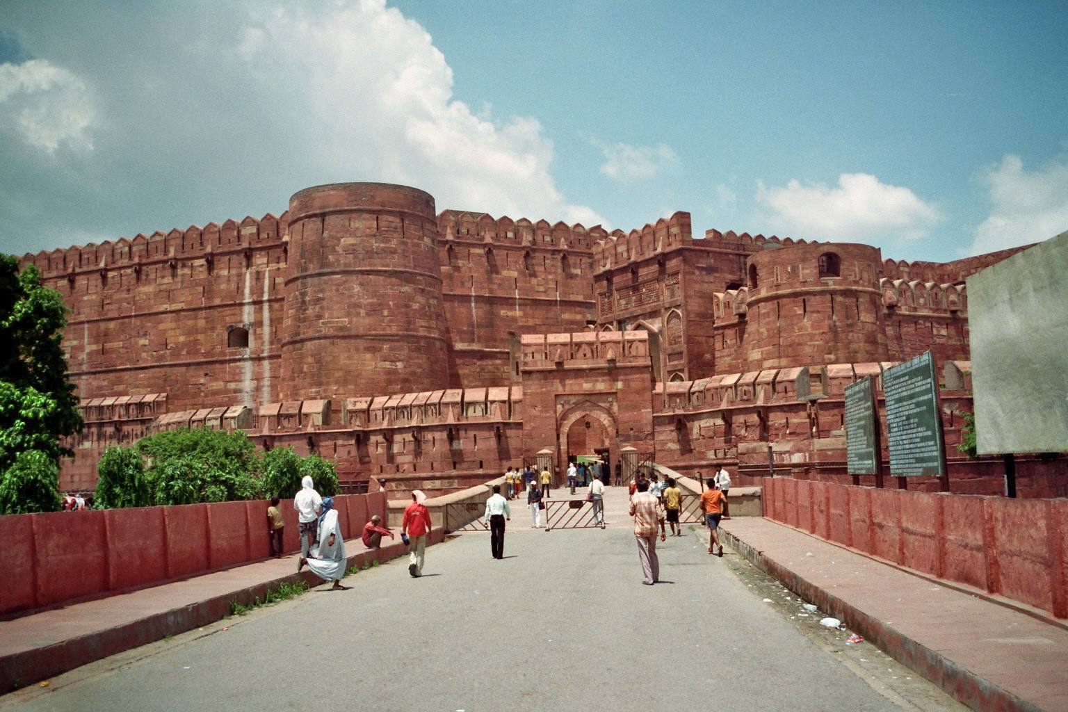 Tourists walk toward Agra Fort's massive red sandstone ramparts