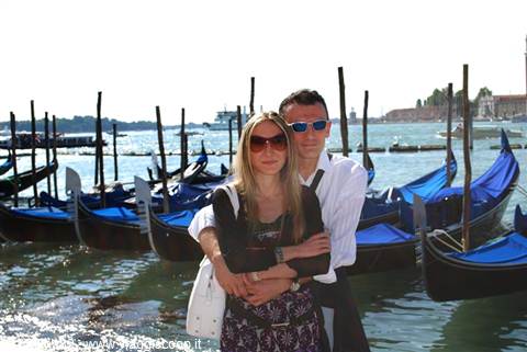 Couple embracing in front of covered gondolas in Venice