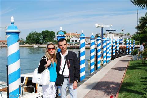 Couple posing beside blue and white striped mooring poles, Venice lagoon