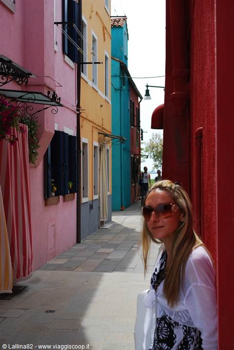 Woman with sunglasses beside colorful houses, looks like Burano