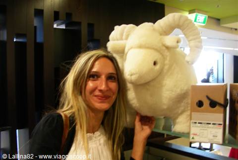 Blonde woman next to a large white stuffed sheep