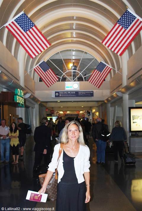 Woman with passport at airport under American flags on arched ceiling
