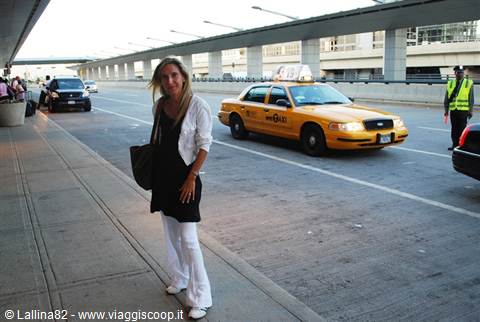 Blonde woman under the airport terminal overpass, yellow Ford Crown Victoria taxi passing by