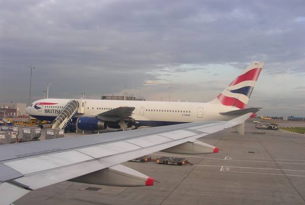 British Airways Boeing 767 with boarding stairs at the airport, wing in foreground, grey light